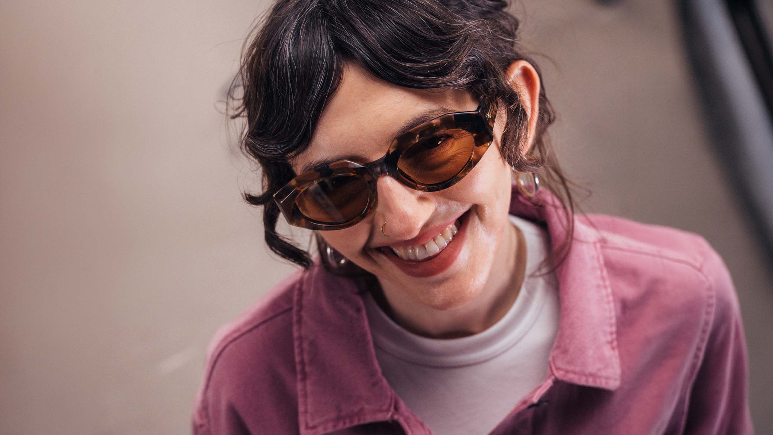 Nuori nainen hymyilee aurinkolasit kasvoilla.