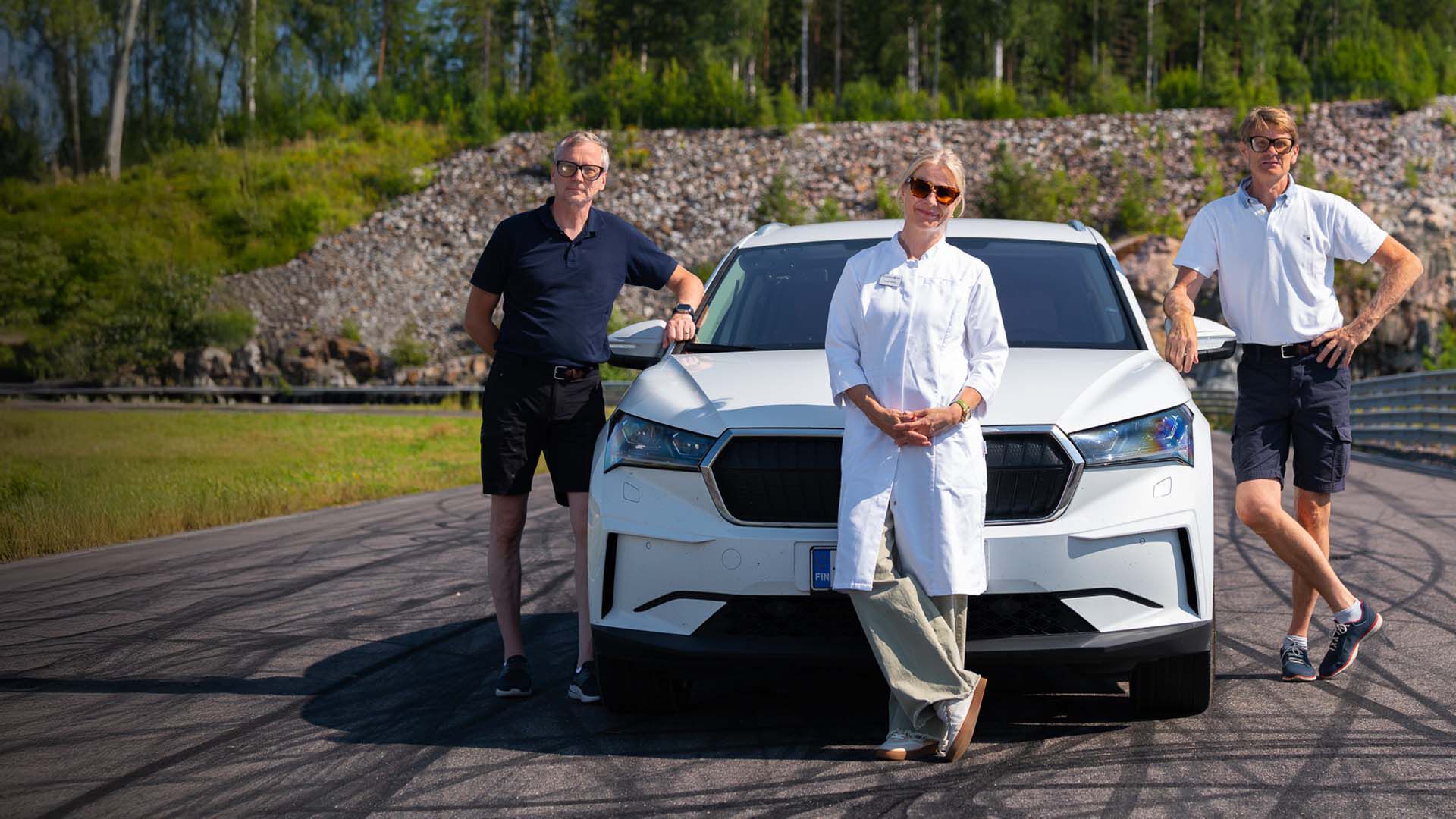 Marcus Grönholm, Timo Rautiainen ja Ulla Näpänkangas auton edessä