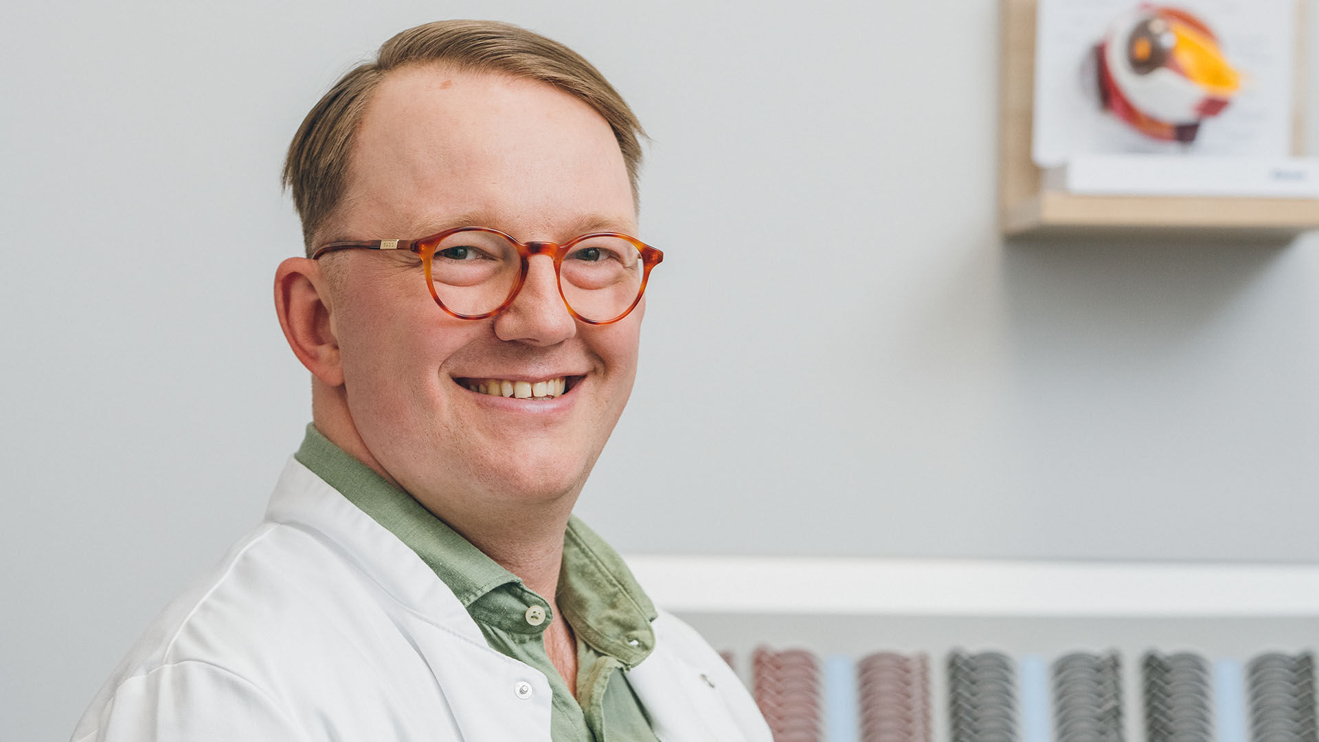 Silm&auml;l&auml;&auml;k&auml;ri oranssit silm&auml;lasit kasvoillaan vastaanottohuoneessa