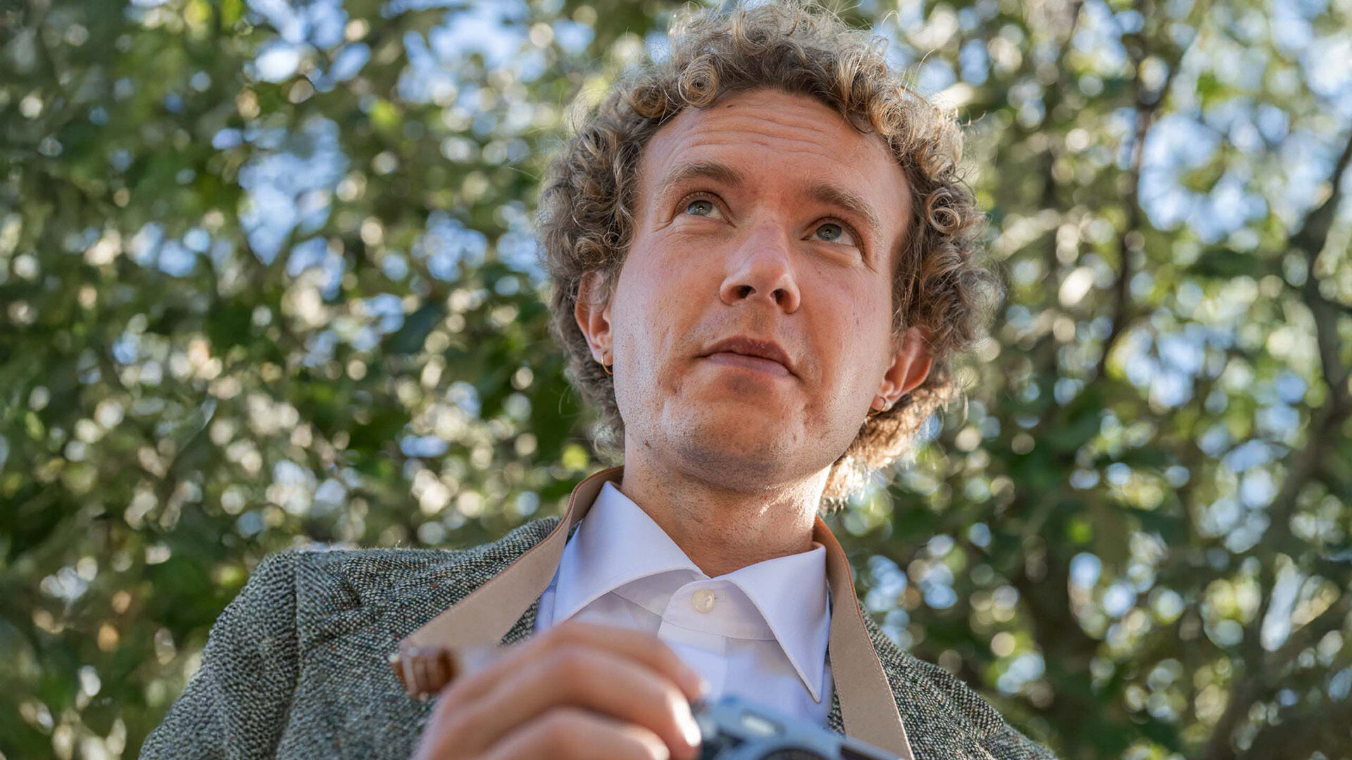 Man wearing contact lenses outdoors, holding a camera.