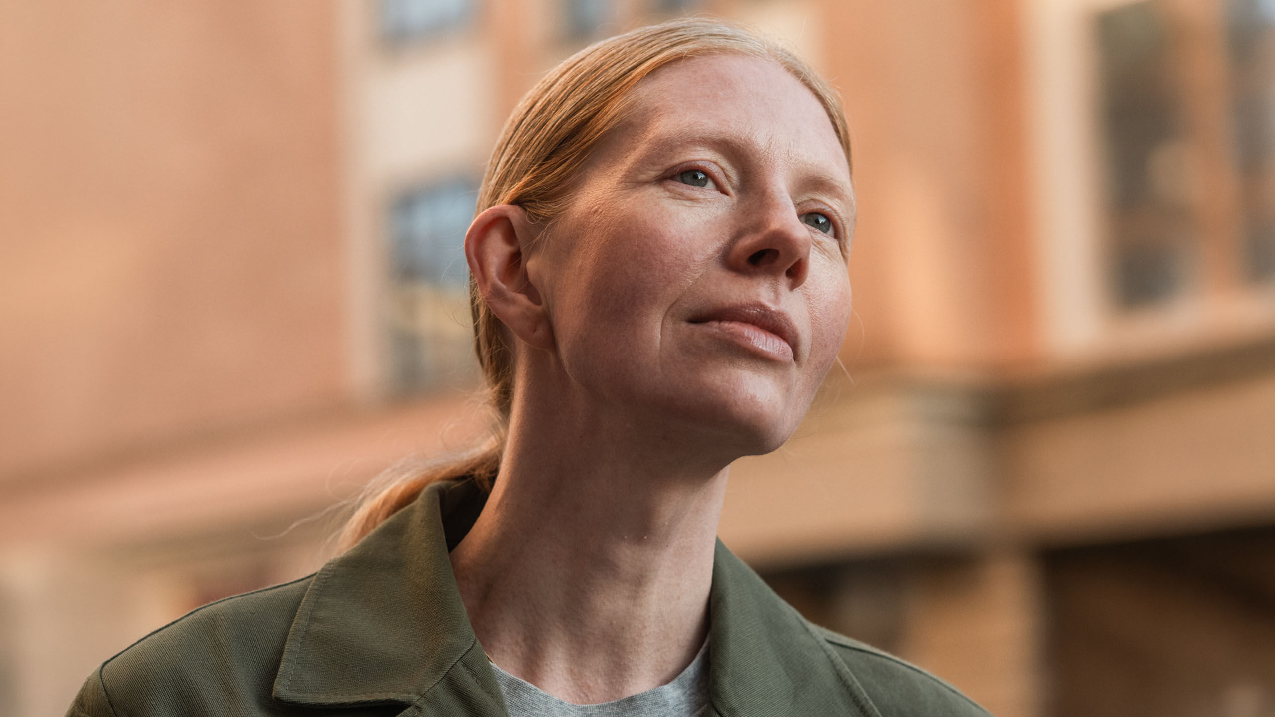 Nainen katselee taivaalle kaupungin keskustassa.