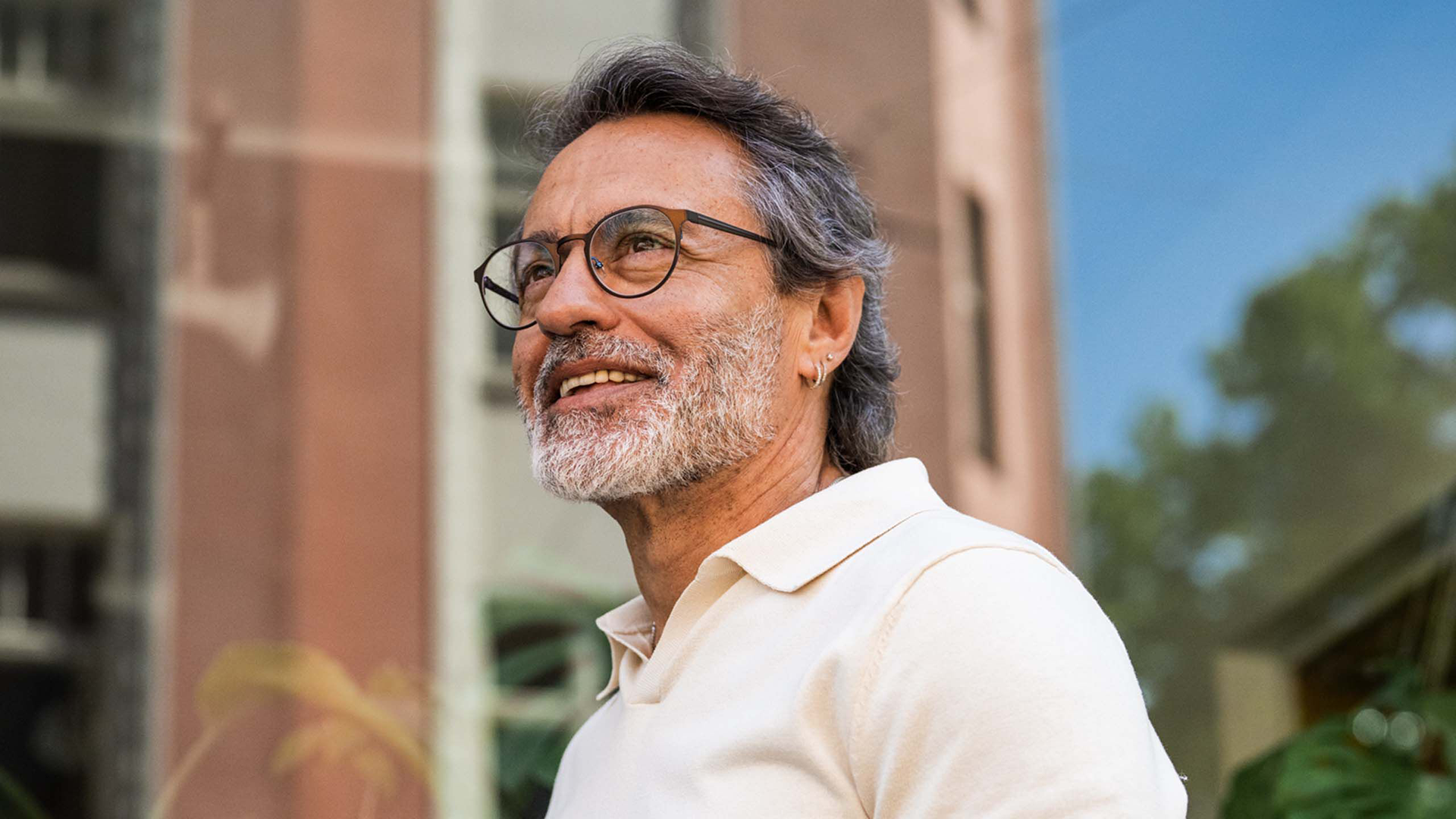 Man wearing glasses, smiling outdoors.
