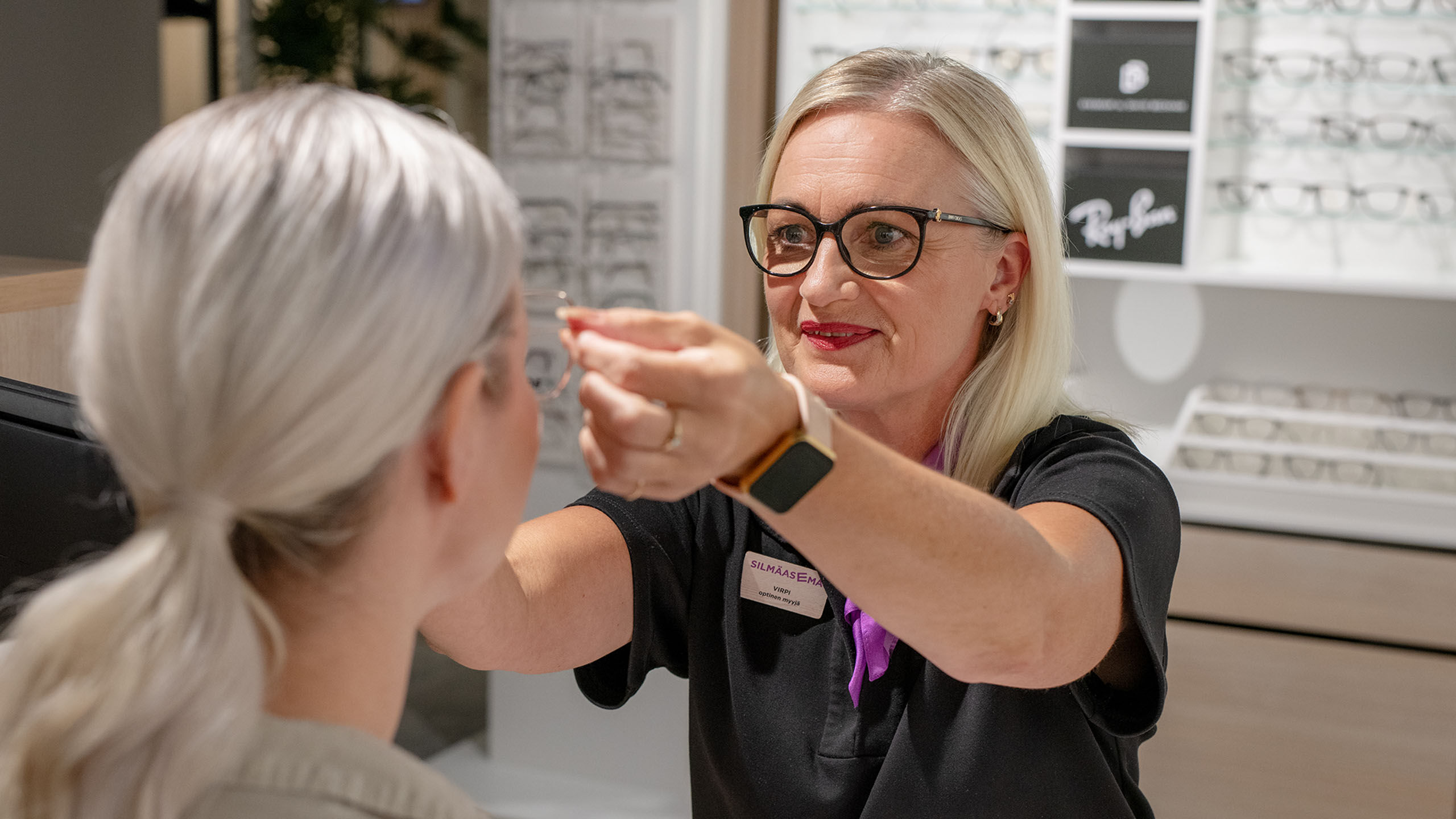 Asiantuntija sovittaa asiakkaalle kehyksi&auml; myym&auml;l&auml;ss&auml;.