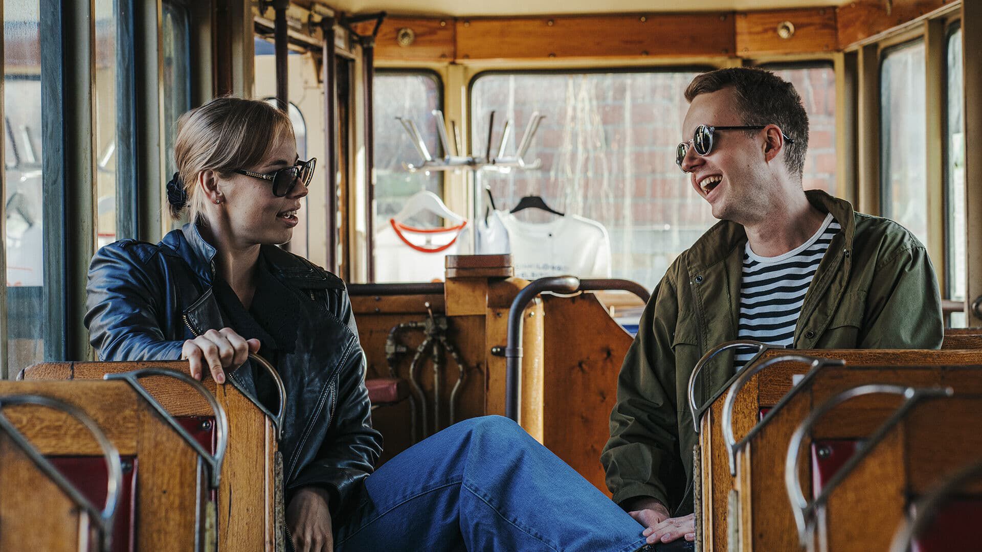 Nainen ja mies vanhassa raitiovaunussa, aurinkolasit kasvoilla