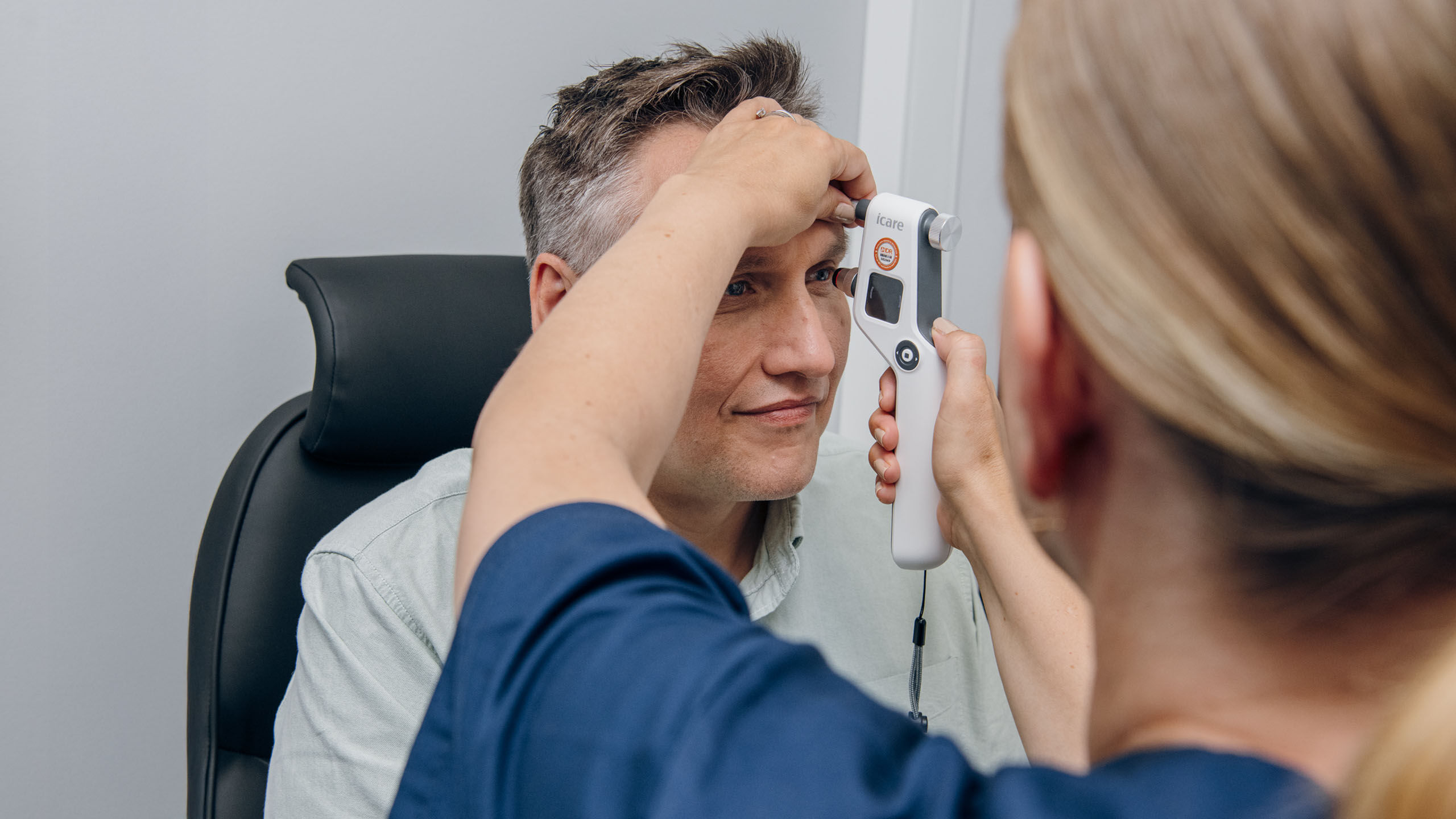 Sairaala optikko tekee asiakkaalle silm&auml;npaineen mittauksen.