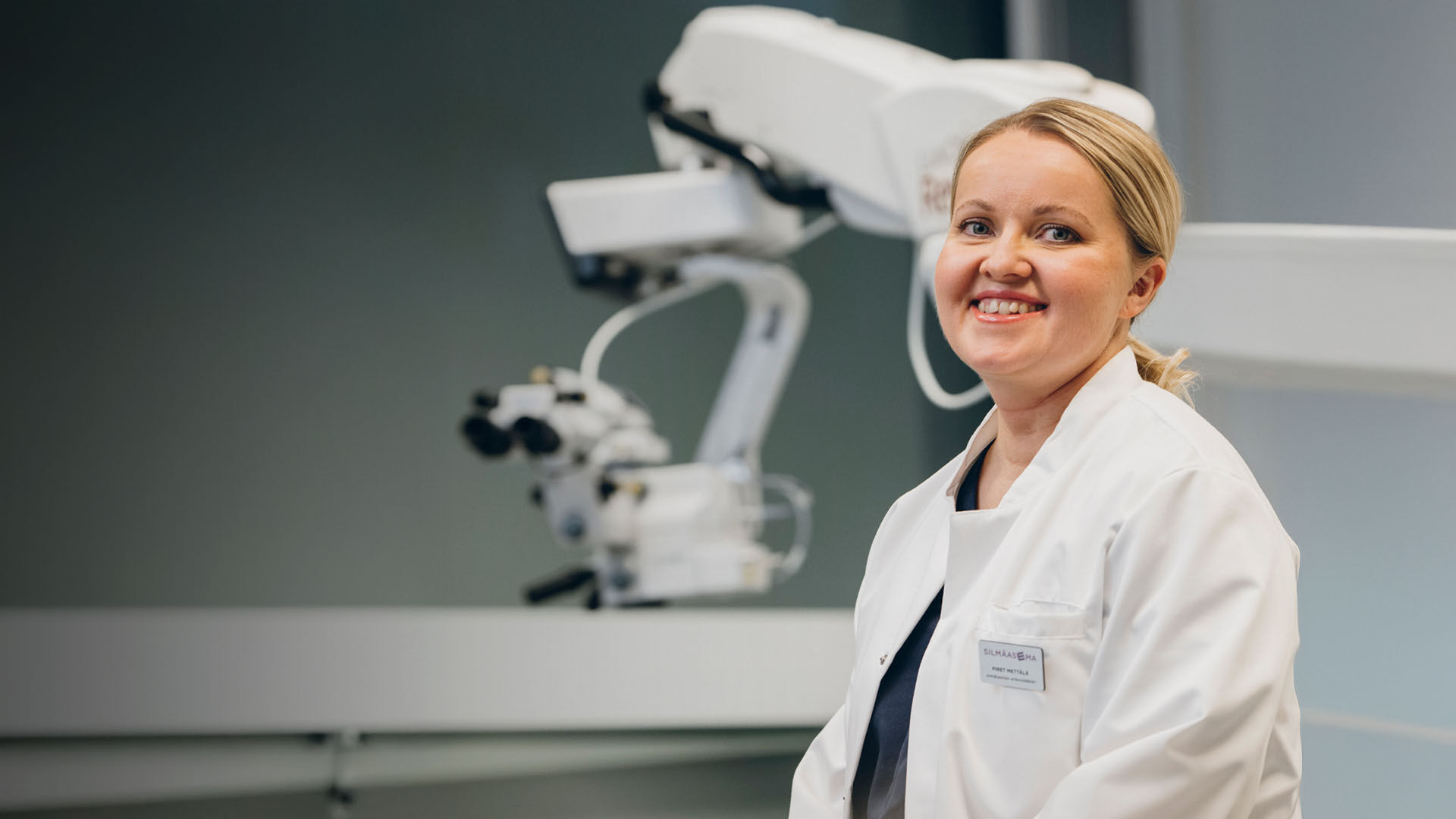 Silm&auml;l&auml;&auml;k&auml;ri hymyilee istuessaan leikkaussalissa