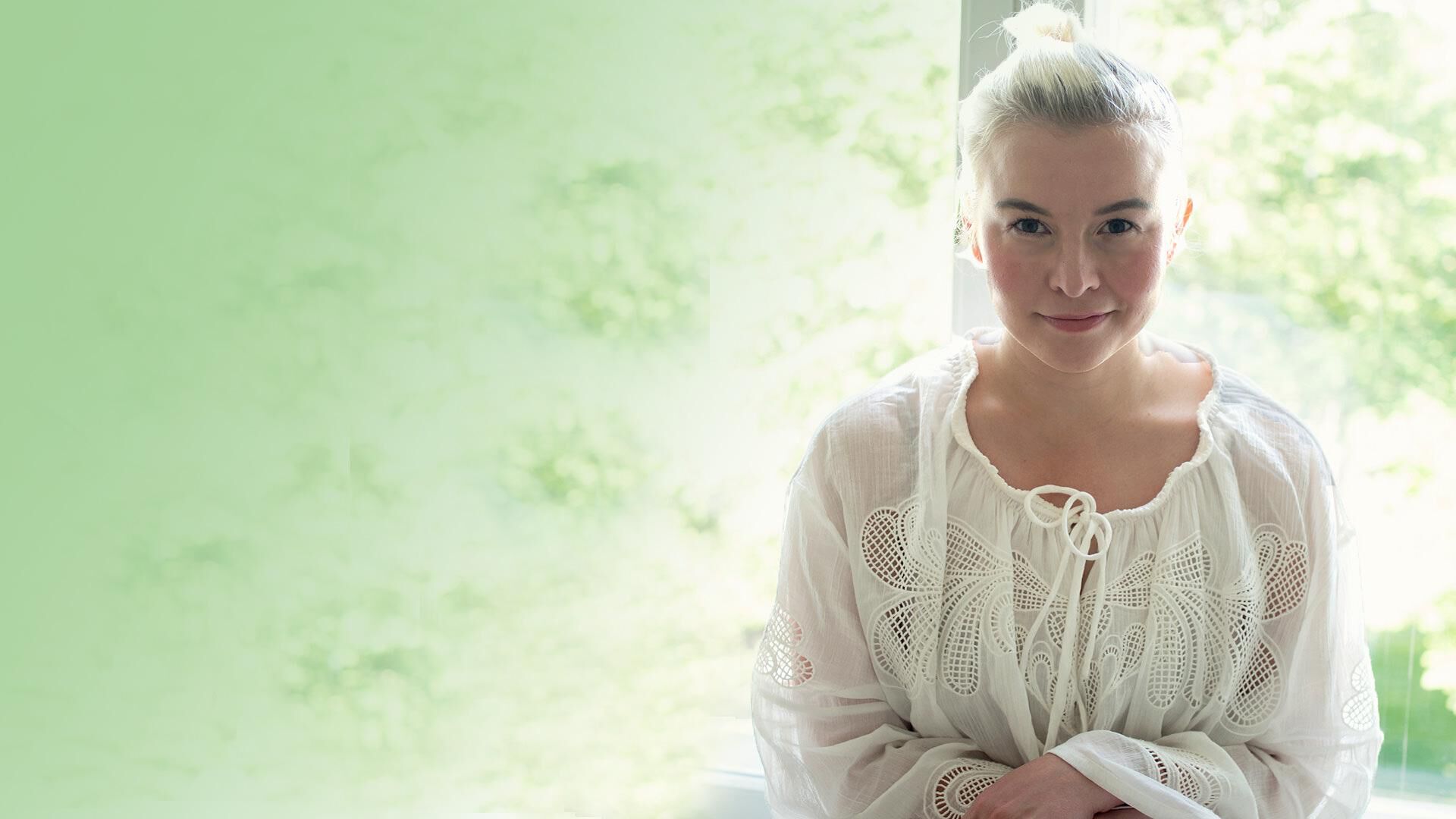 Toimittaja ja bloggaaja Jenna K&auml;m&auml;r&auml;inen istuu ikkunan edess&auml;