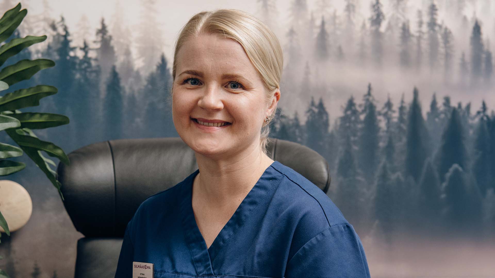 Silmähoitaja hymyilee kameralle lepohuoneessa