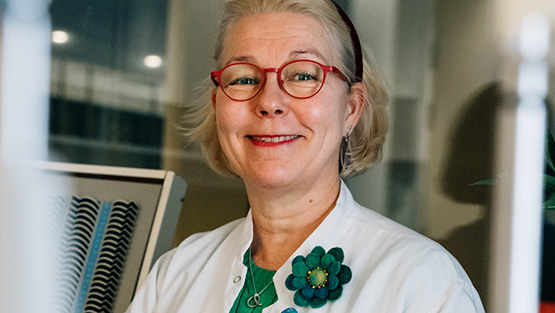 Ystävällisesti hymyilevä lasten silmälääkäri punaisissa silmälaseissa