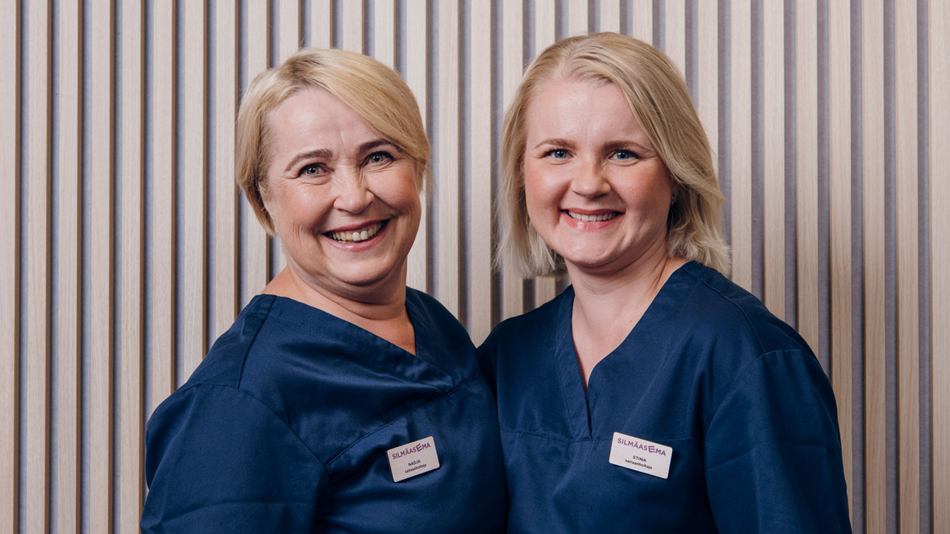 Kaksi silmäsairaalan hoitajaa hymyilevät kameralle iloisesti