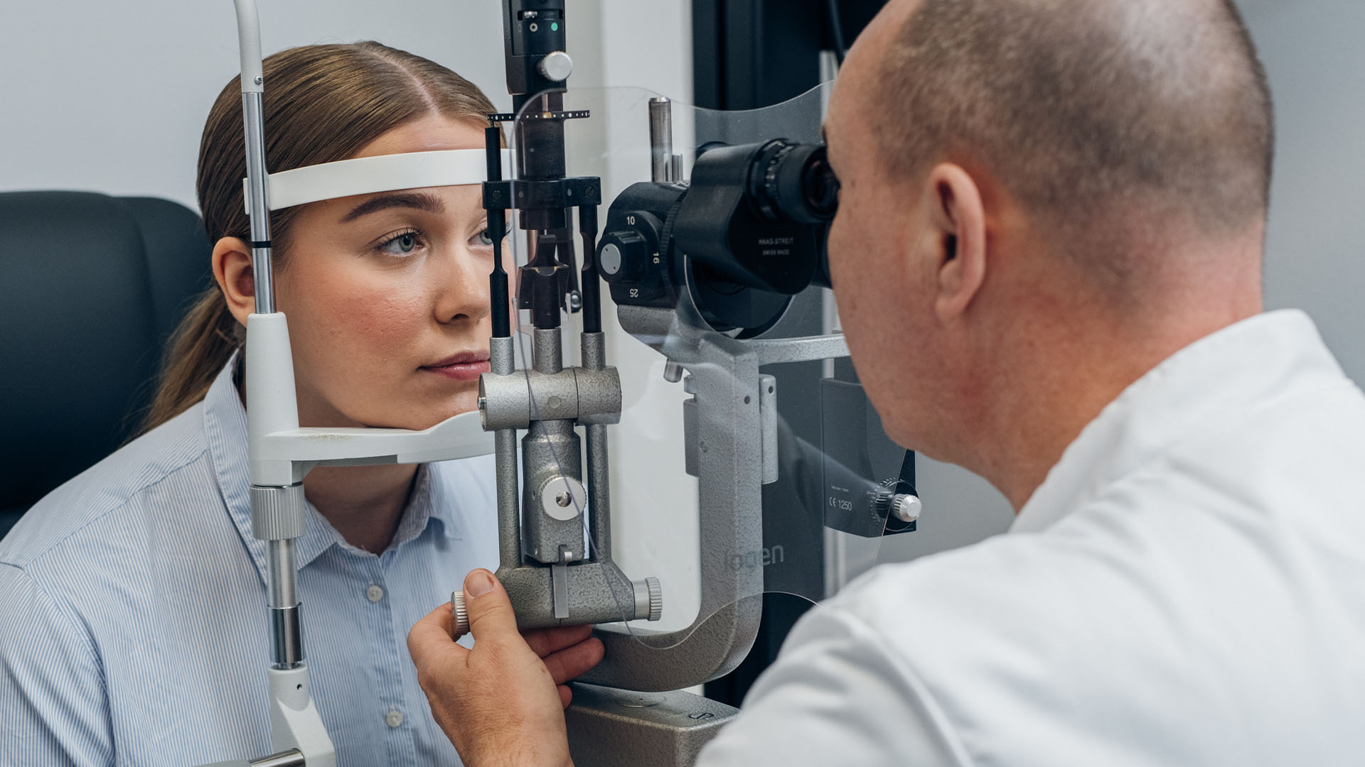 Nuori nainen silmälääkärin mikroskopoitavana vastaanottohuoneessa