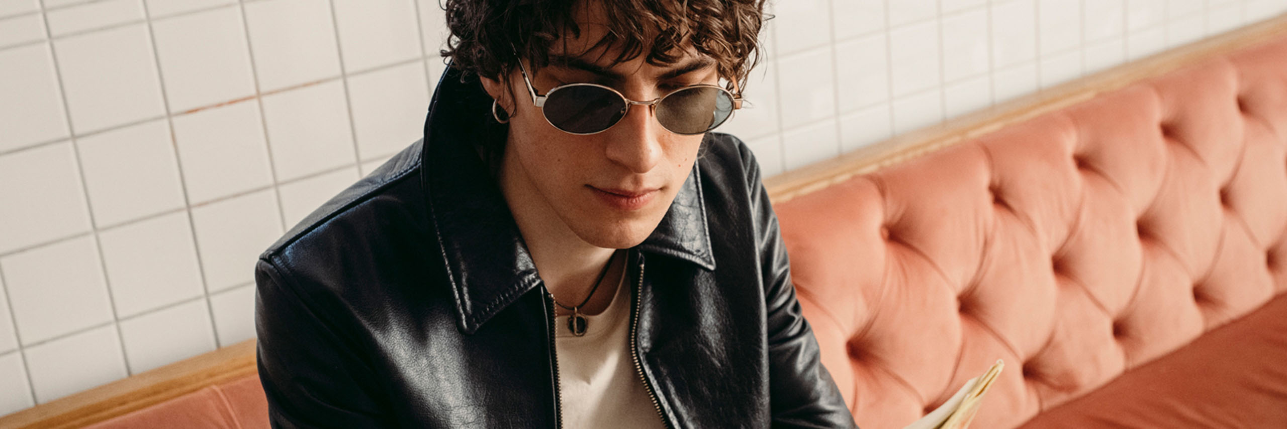 Mies istuu sohvalla aurinkolasit päässä