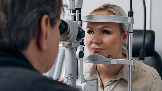 Nuori nainen tutkimushuoneessa tutkimuslaitteen takana