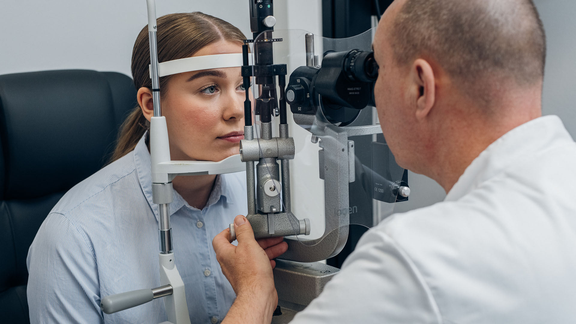 Silmälääkäri tutkii nuoren asiakkaan silmiä mikroskoopilla
