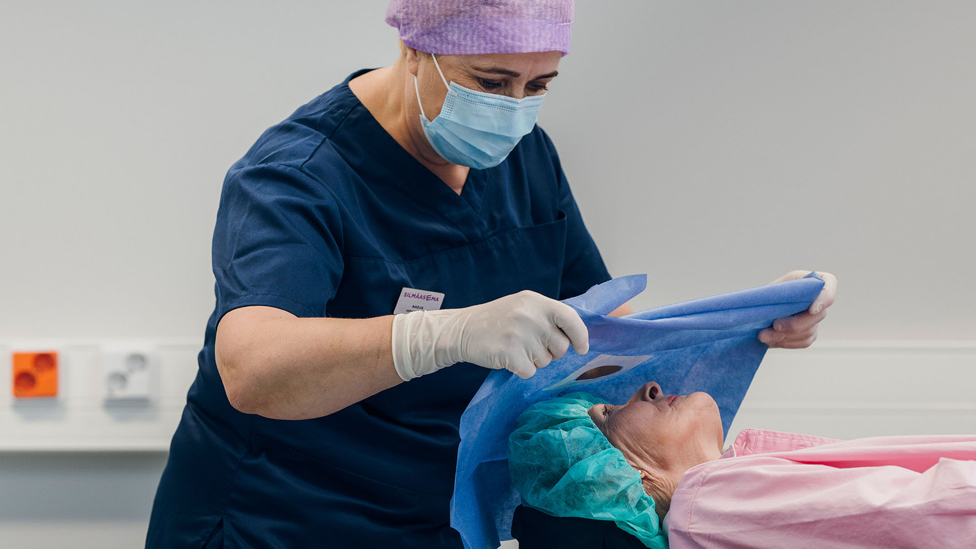 Hoitaja valmistelee asiakasta kaihileikkaukseen leikkaussalissa