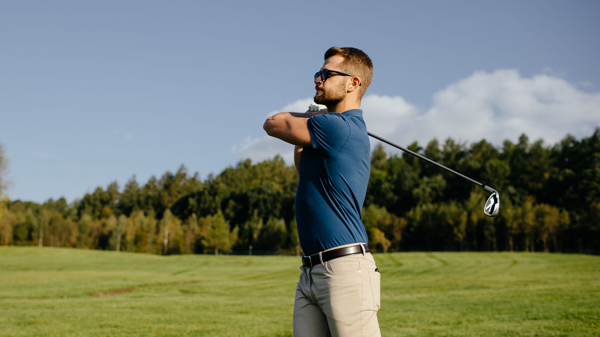 Mies golfaamassa aurinkolasit päässä.