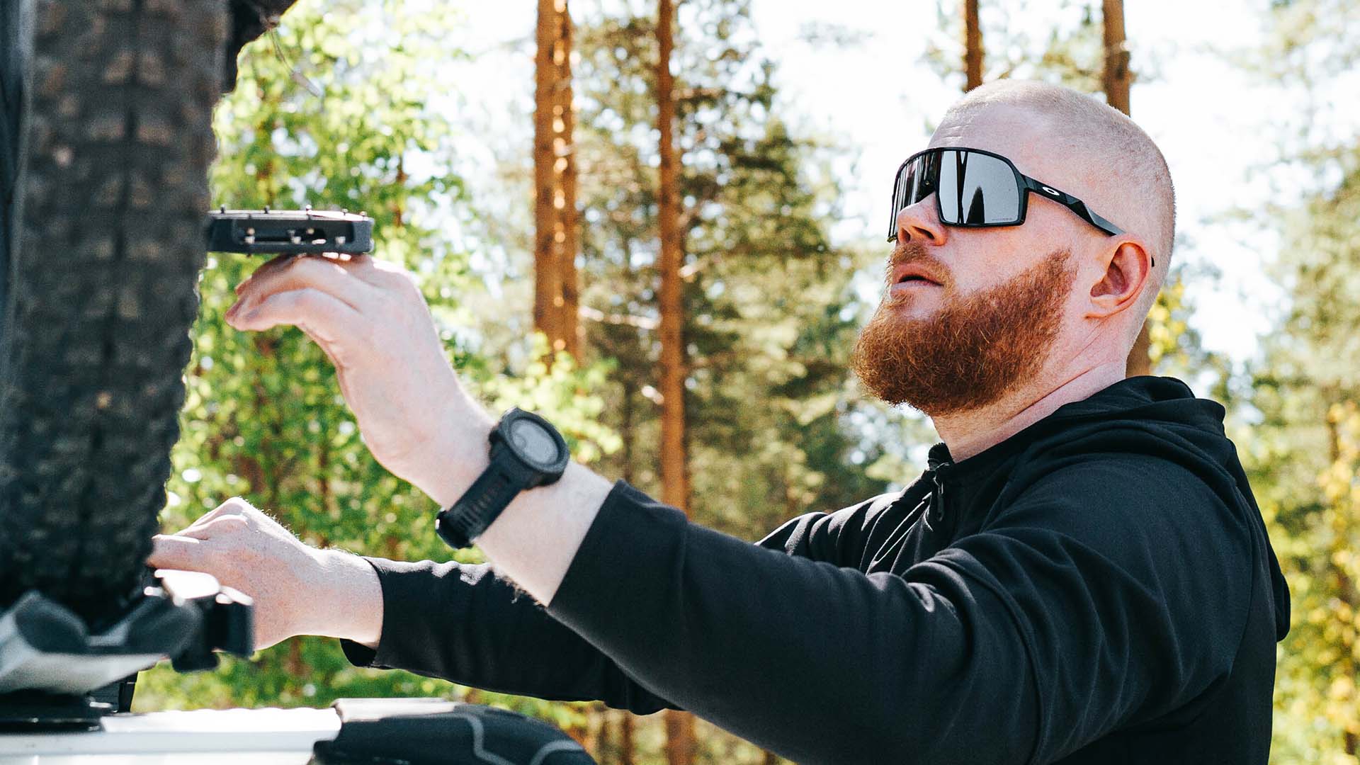 Urheiluaurinkolasit päässä pyörää korjaava mies.