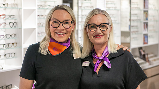 Kaksi optikkoa toivottaa tervetulleeksi myymälään