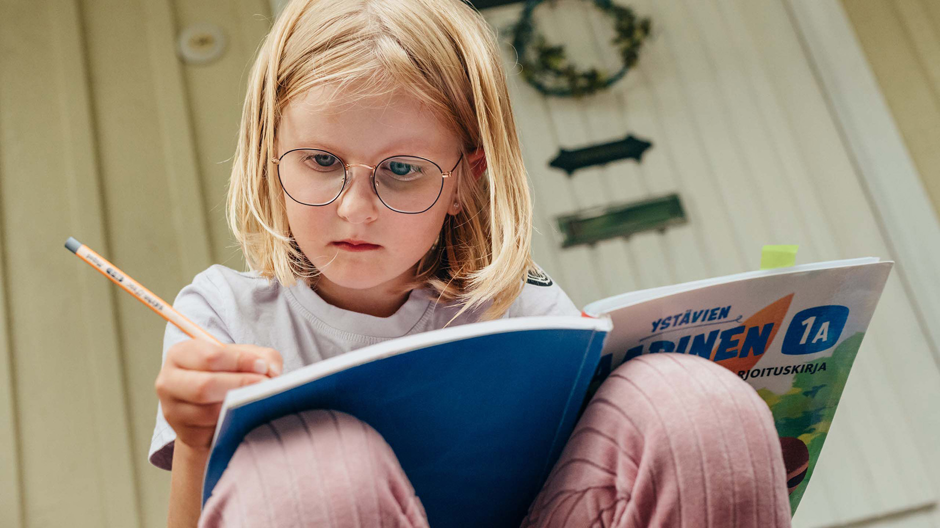 A child wearing glasses doing their homework.