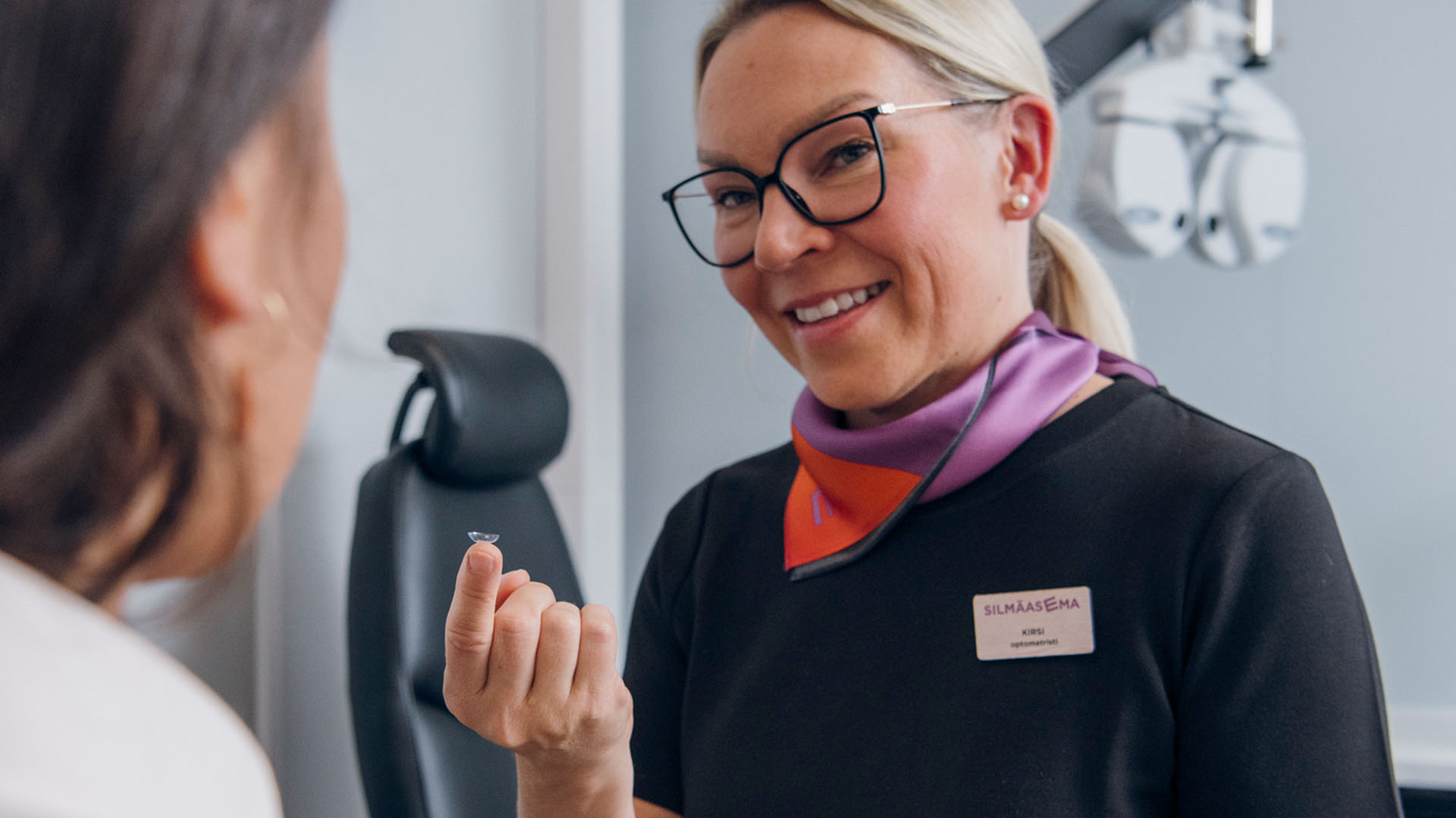 Optikko ja asiakas piilolinssien ensisovituksessa näöntutkimushuoneessa.