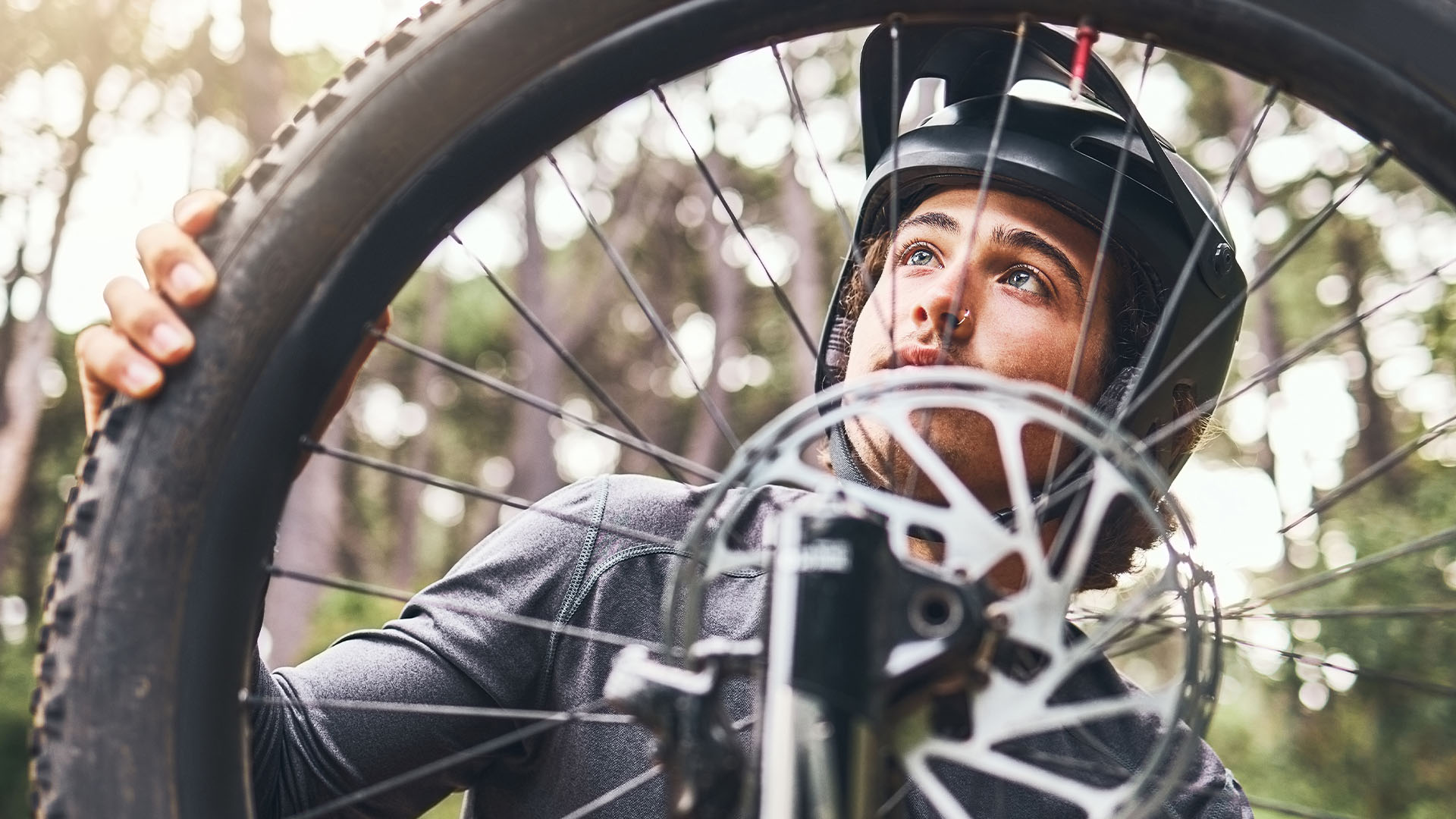 Pyörän rengasta tutkiva maastopyöräilijä