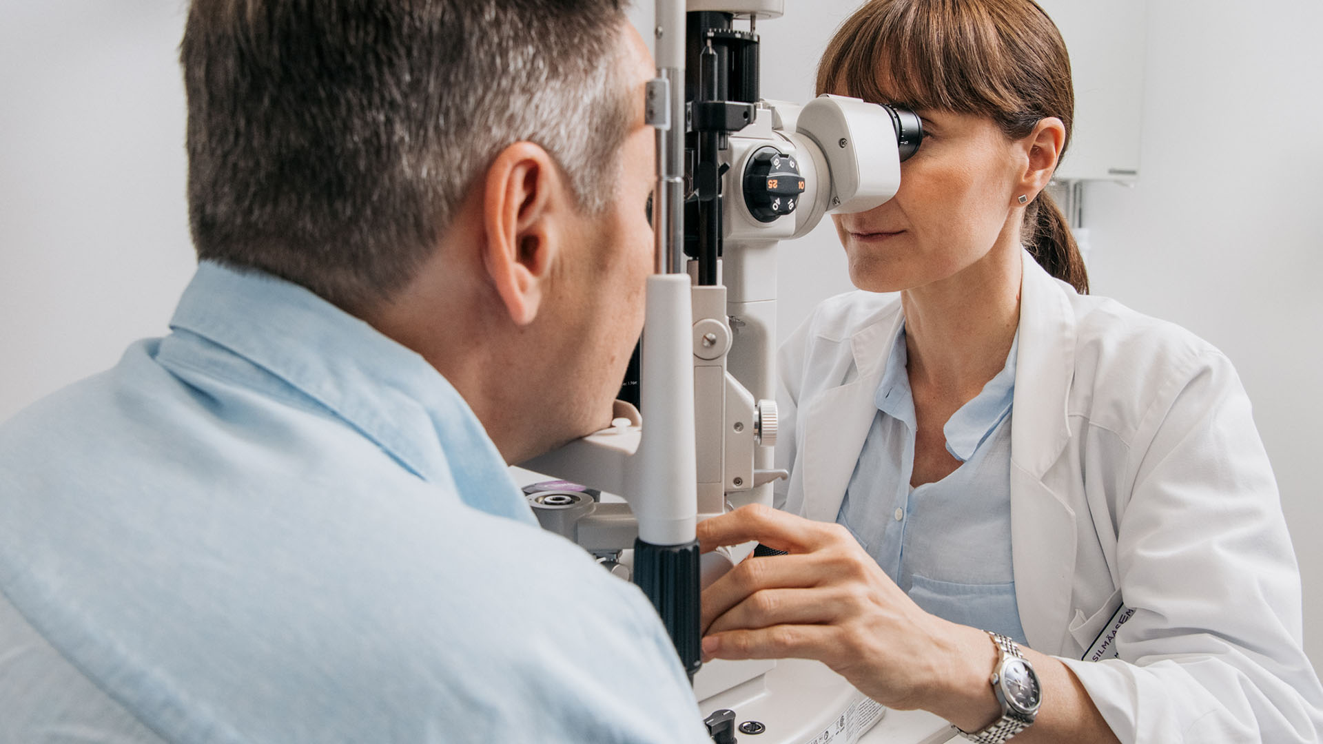 Silmälääkäri tutkii kuivasilmäisyydestä kärsivän asiakkaan silmiä