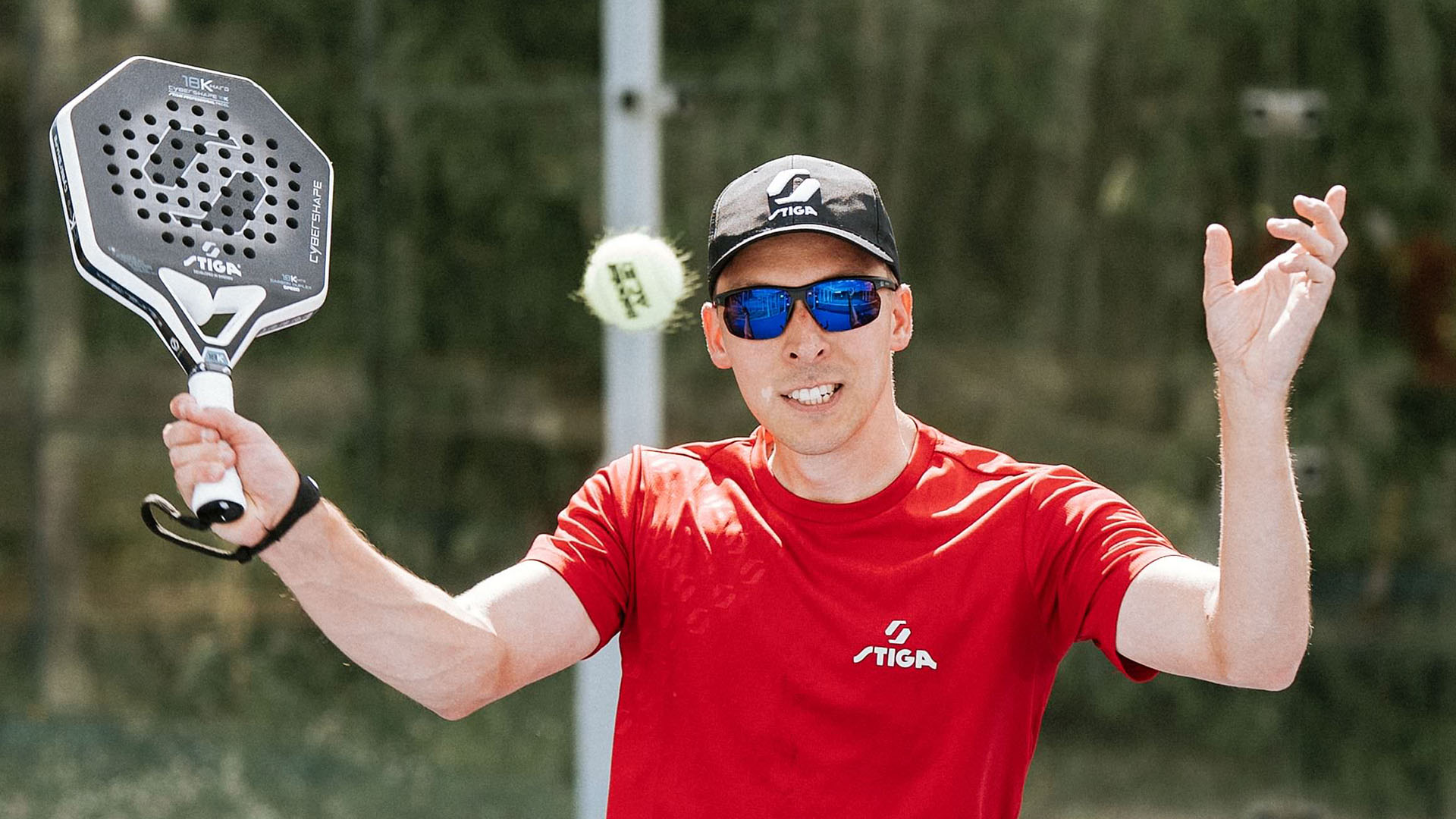 Padel-pelaaja urheiluaurinkolasit kasvoilla pelaamassa