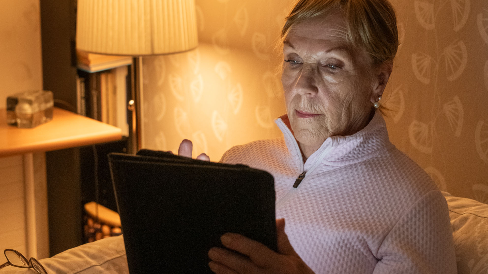 Kaihileikkauksessa käynyt rouva selaa tablettia sängyssään