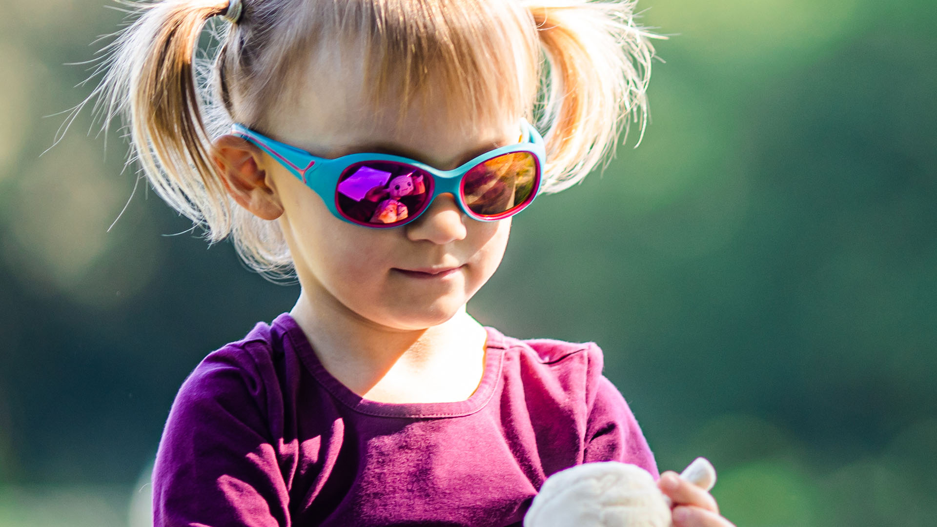 Aurinkolasit päässä oleva saparopäinen lapsi ulkona
