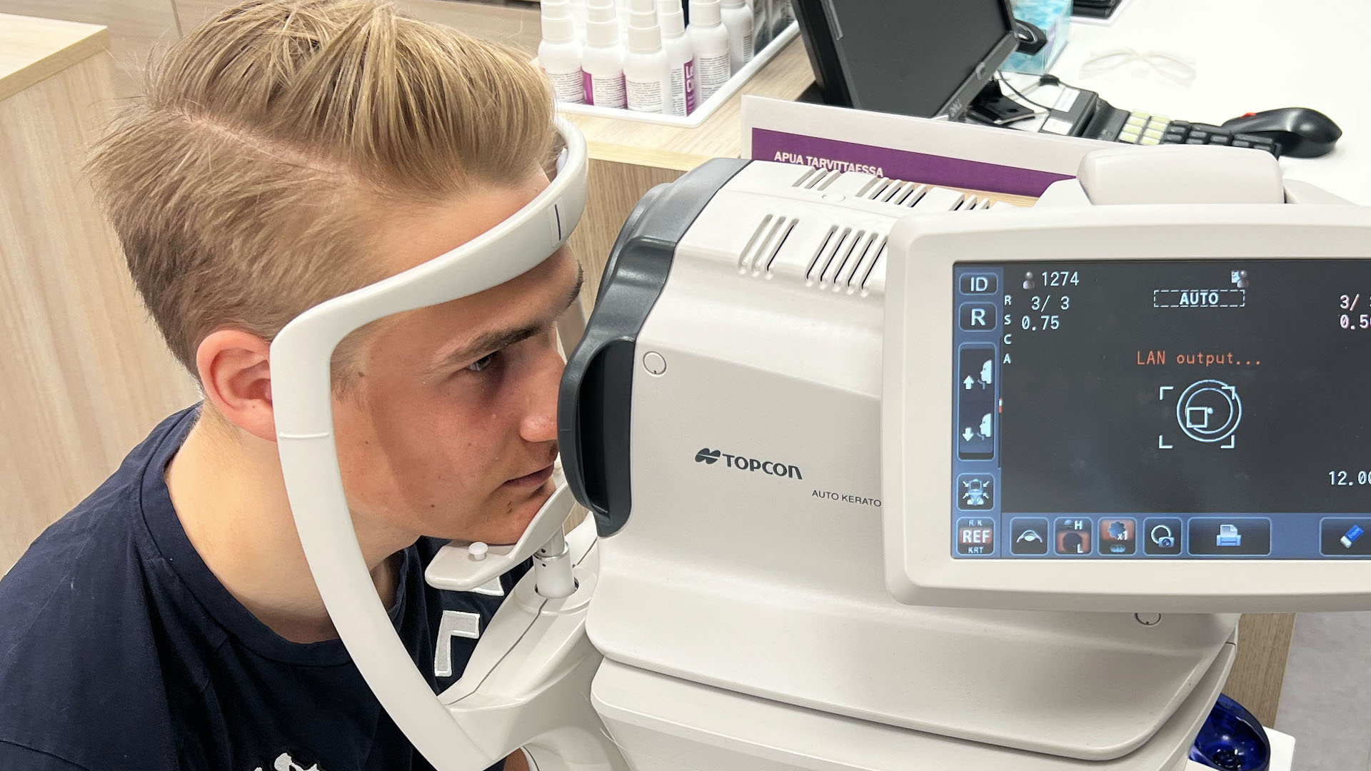 Alppihiihtäjä optikon urheilunäkötutkimuksessa tutkimuslaitteen takana