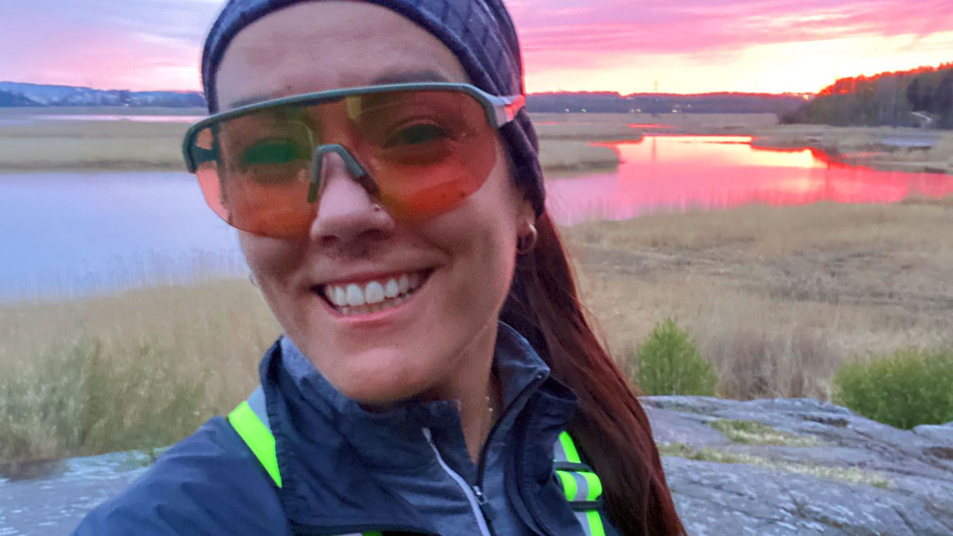 Hanne Valtari sporttiset urheiluaurinkolasit kasvoilla kameralle hymyillen.