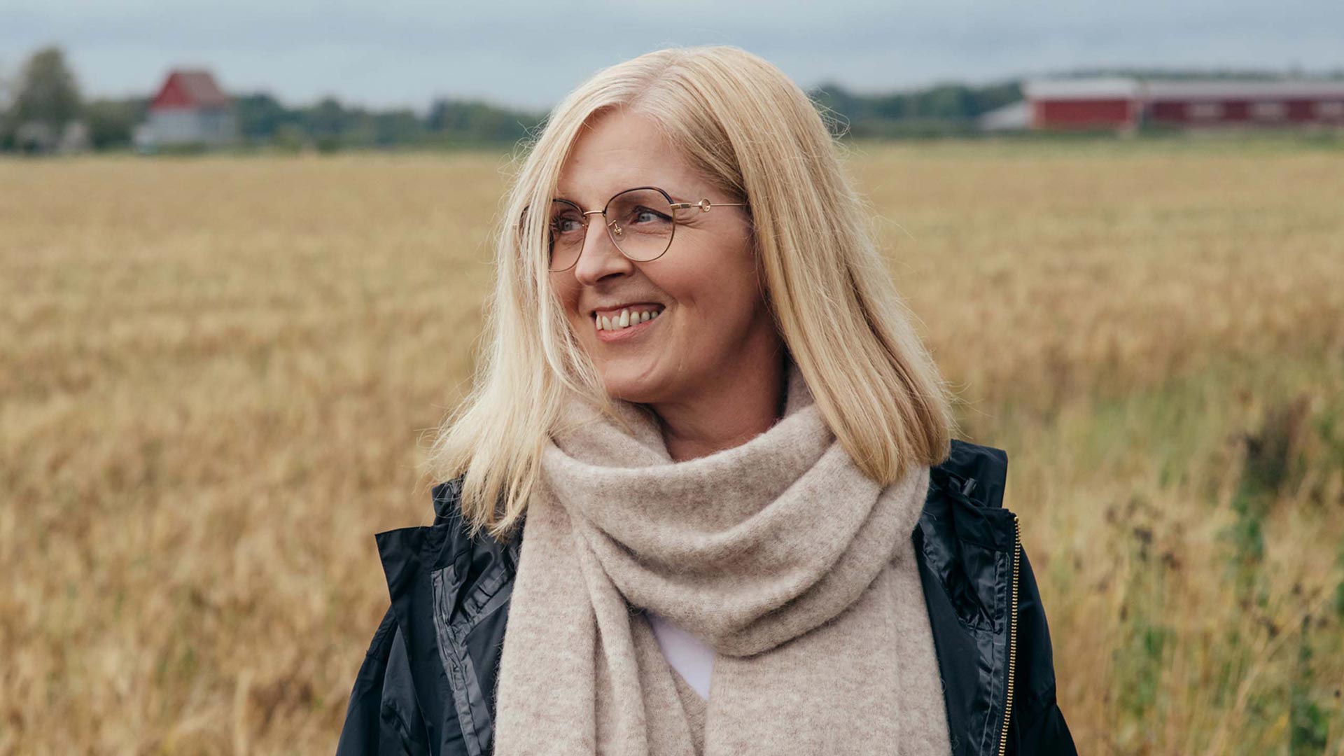 Silmälasipäinen nainen pellonreunalla