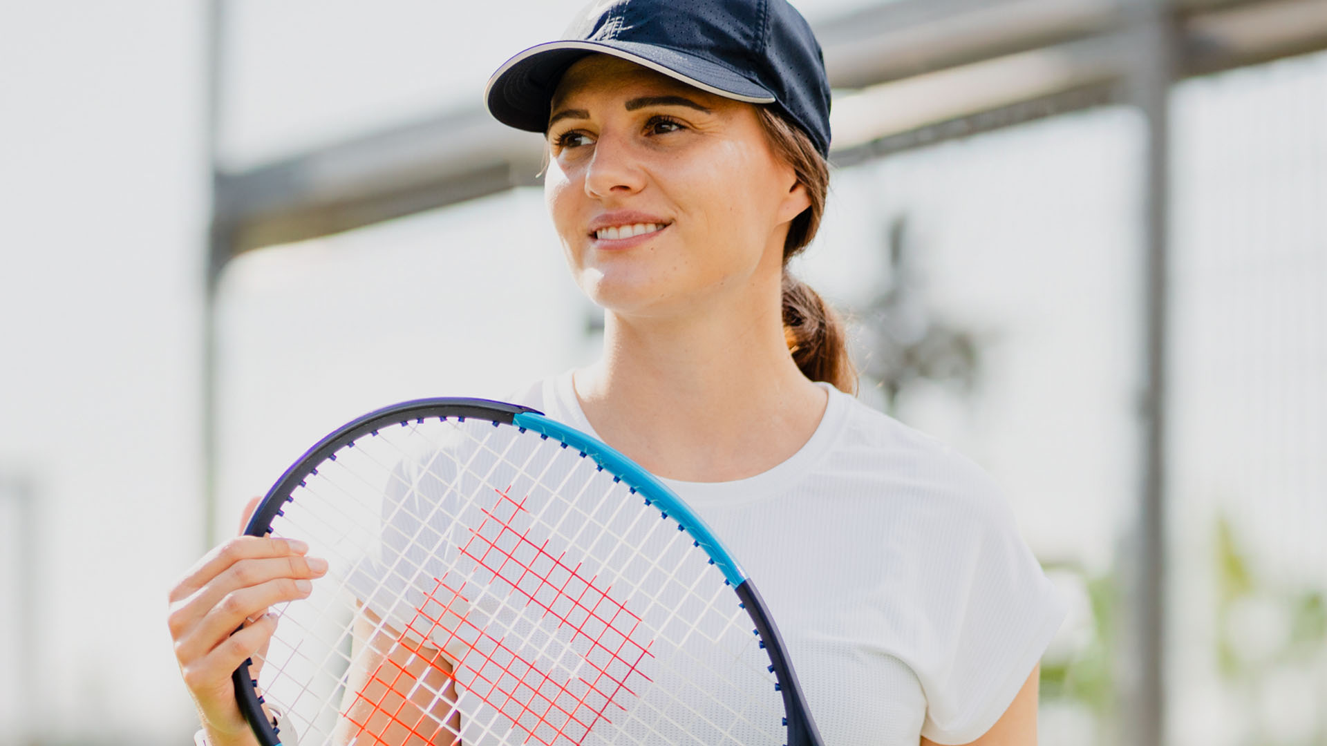 Piilolinssit päässä oleva nuori nainen tenniskentällä.