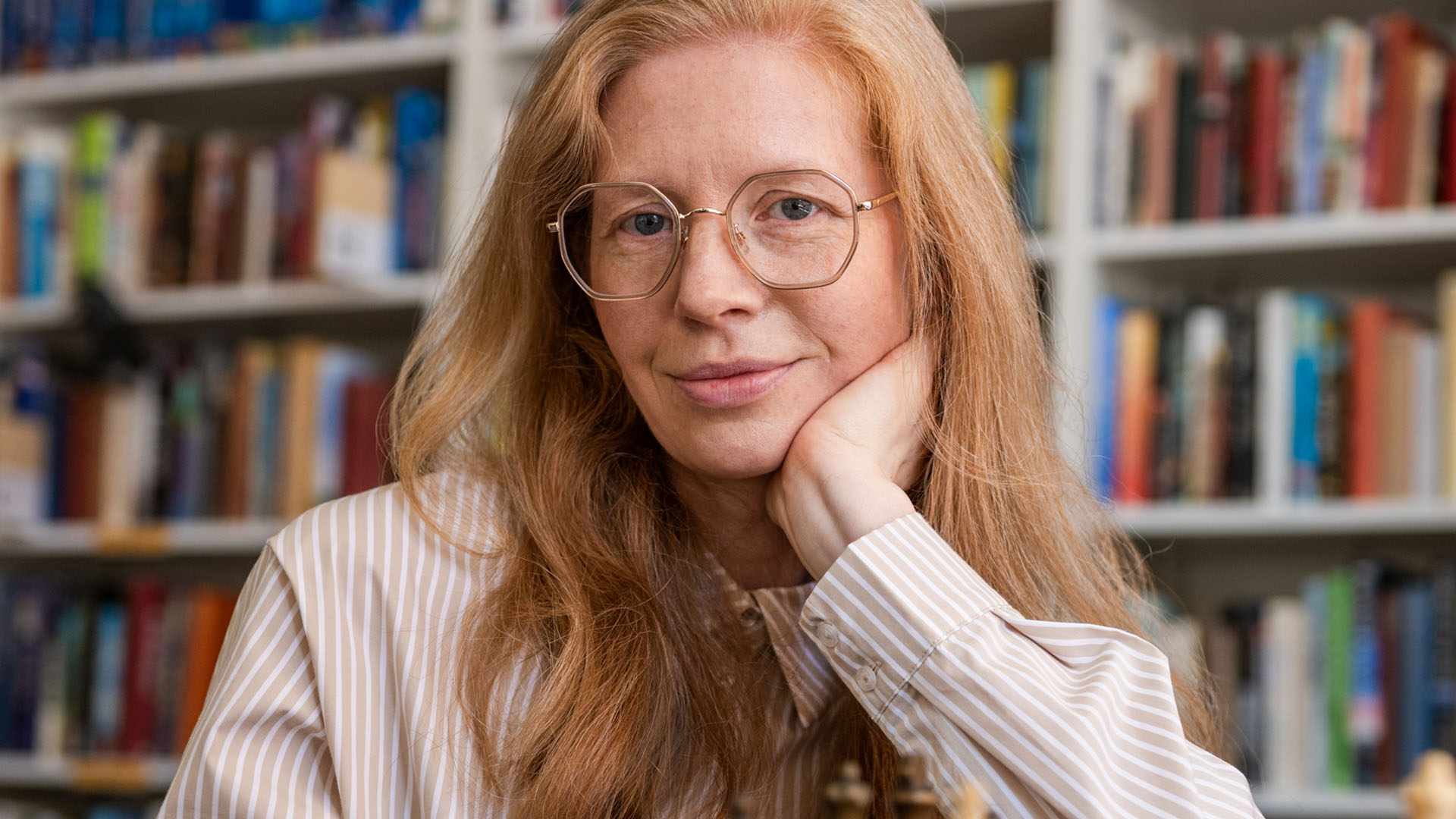 Vaaleat kehykset kasvoilla kameralle poseeraava punatukkainen nainen