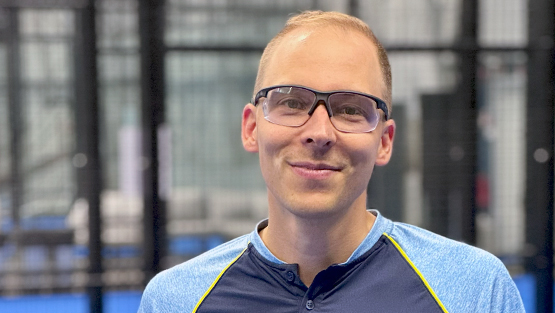 Urheilulasit päässä oleva padel-pelaaja hymyilee kameralle
