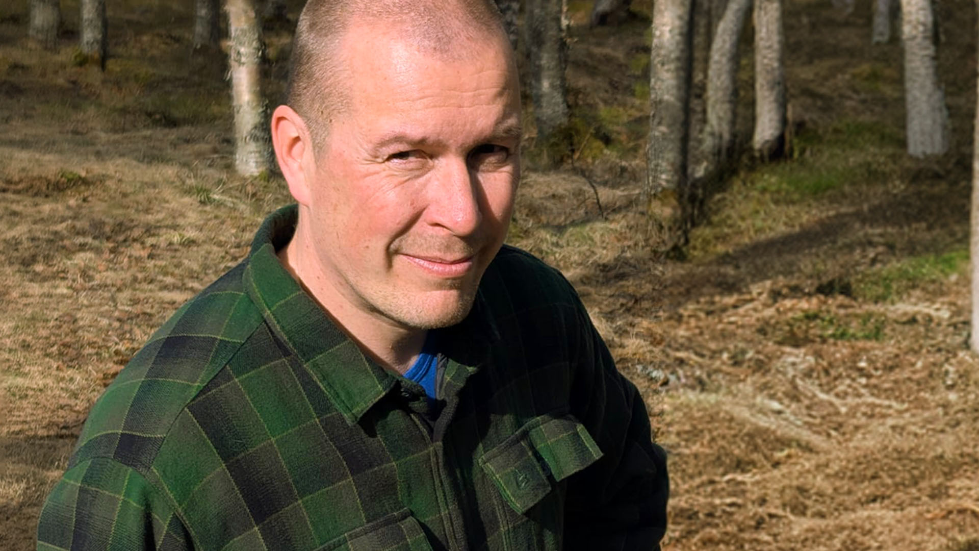 Aki Törmänen hymyilee kameralle metsässä.