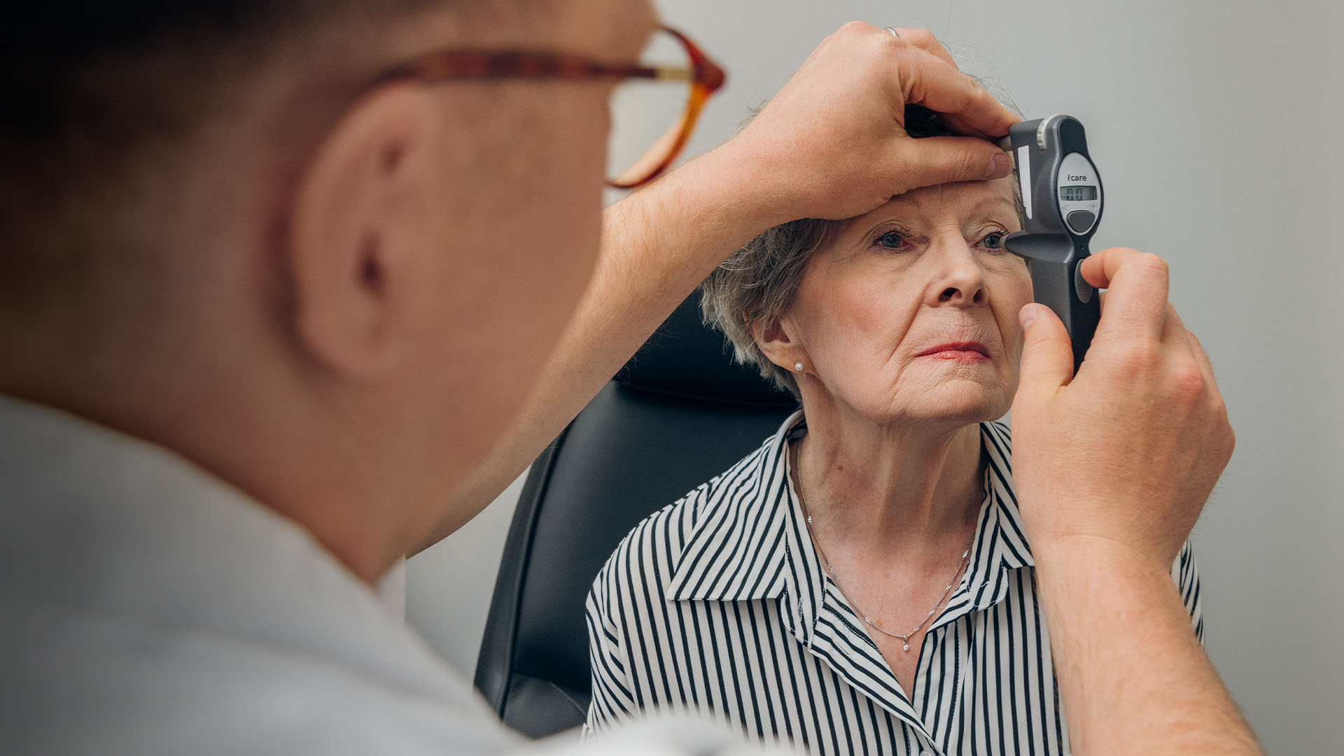 Vanhempi rouva mittauttaa silmänpainetta lääkärin vastaanotolla